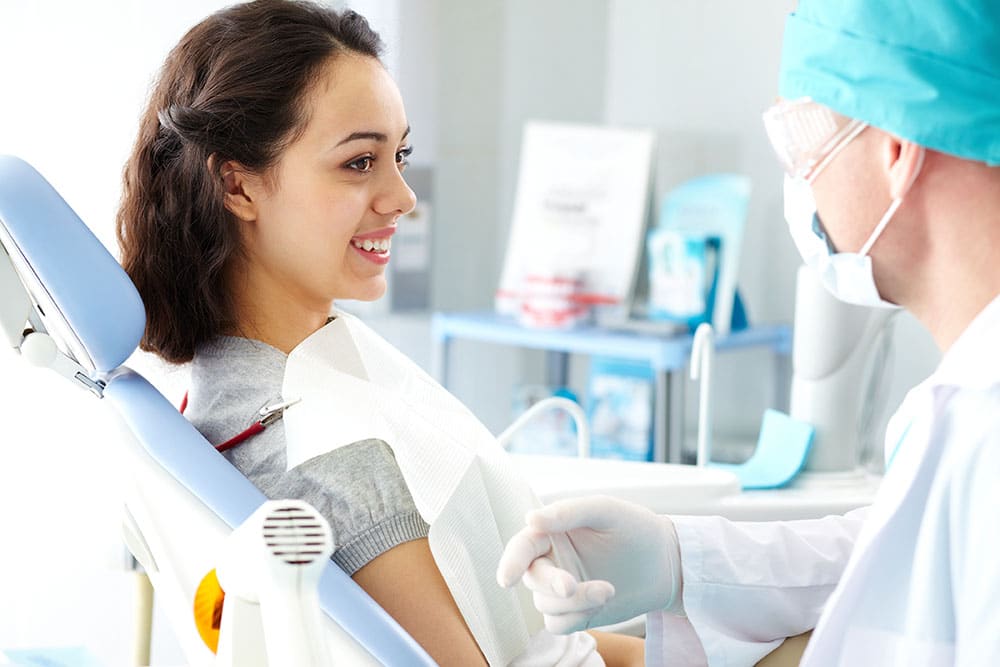 dentist talking with girl holding intraoral camera